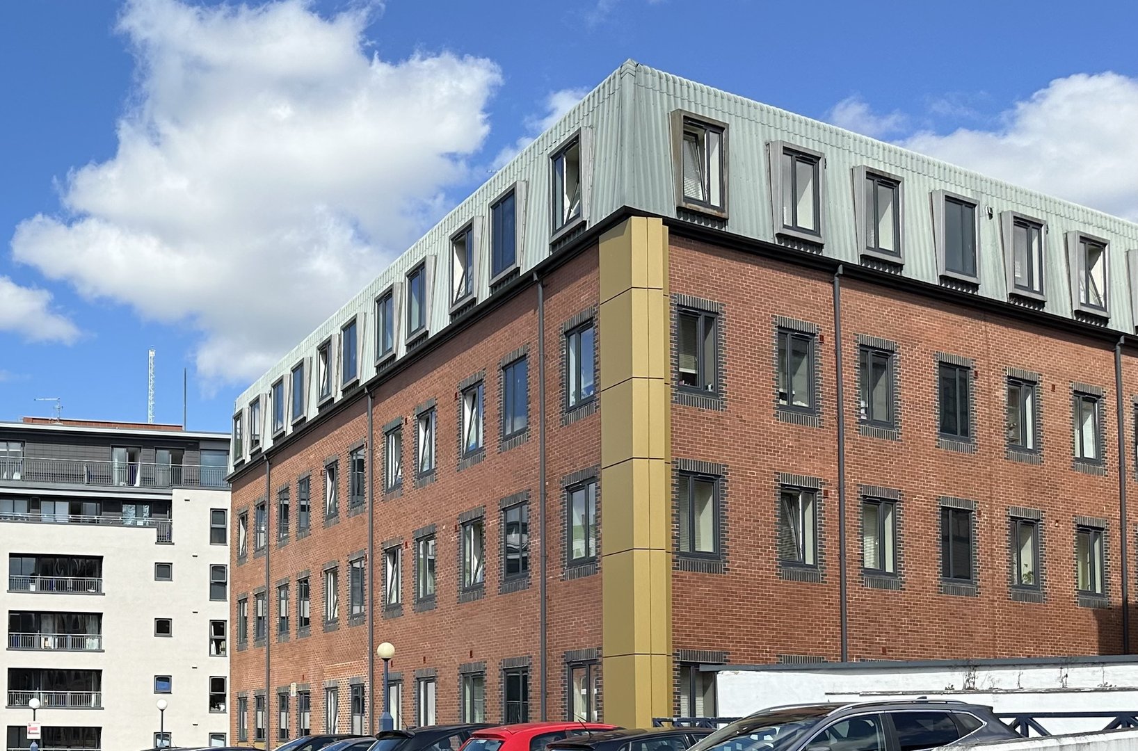 Red-brick residential building in central Newcastle under a blue sky